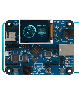 An electronic development board is displayed, featuring a small screen that shows "Electric Vehicle Charging" with a gauge indicator reading 25%. The board includes various ports and components, indicating its functionality for programming or hardware projects.