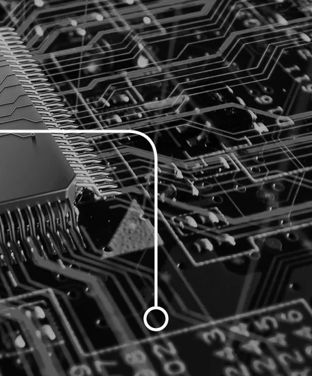 A close-up of a circuit board featuring a microchip with numerous connecting pins. The background displays intricate patterns of pathways and components typical of electronic circuitry, highlighting the technology's complexity and design.