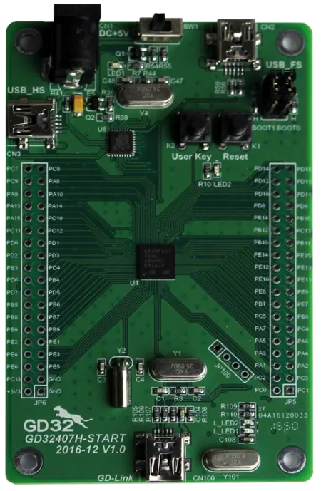 An electronic development board with a green circuit, featuring multiple pins, USB ports, and buttons labeled "User Key" and "Reset." The center contains a microcontroller and various components, designed for programming and prototyping electronic projects.
