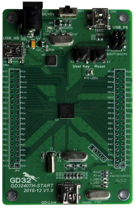 An electronic development board with a green circuit, featuring multiple pins, USB ports, and buttons labeled "User Key" and "Reset." The center contains a microcontroller and various components, designed for programming and prototyping electronic projects.