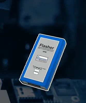 A blue and gray programming device labeled "Flasher" for ARM microcontrollers. The front features buttons and indicators for status: "Ready," "Not ready," and "Fail." It is shown against a blurred background of electronic components, highlighting its function in programming hardware.