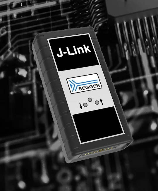 A J-Link Base device is prominently displayed against a dark, textured background resembling a circuit board. The device has a rectangular shape and features the text "J-Link" and "BASE" on the front, along with a logo labeled "SEGGER."