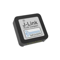 The image shows a compact J-Link PLUS device with a rectangular design. It features a white label displaying "J-Link PLUS Compact" and the SEGGER logo, which includes a stylized blue arrow. The device has multiple connection pins on one side.