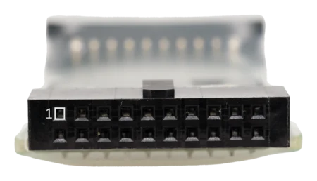 Close-up view of a rectangular black connector with multiple small pinholes, labeled with the number "1." The background is softly blurred, showcasing the connector's details against a light surface.