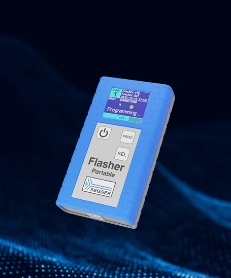 Image of a blue electronic device labeled "Flasher Portable PLUS" from SEGGER. The device features a small screen displaying a programming progress indicator and three buttons: "PROG," "SEL," and a power button. The background is a blend of dark tones with digital patterns.