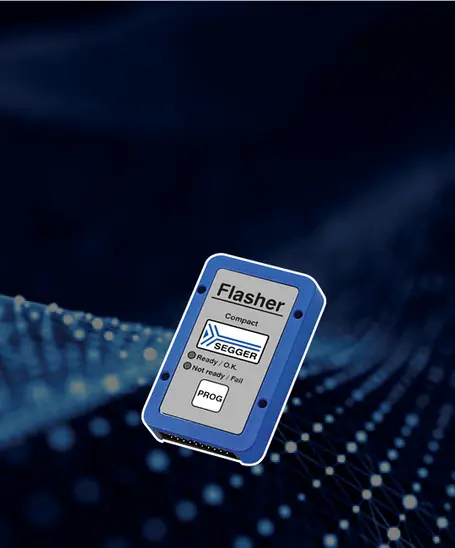 A compact SEGGER Flasher device is displayed, featuring a label with "Flasher" and "Compact" prominently. It includes indicators for status: "Ready / OK" and "Not ready / Fail," along with a "PROG" button. The background is dark with a subtle abstract pattern.