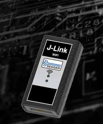 Image of a small, rectangular black device labeled "J-Link WiFi" with indicator lights on the front. The device is positioned against a blurred background of circuit patterns, suggesting a technological or electronic context.