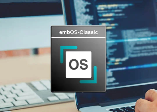 Image of a computer workspace featuring a logo for "embOS-Classic." The logo displays the letters "OS" within a square, surrounded by two arrows. In the background, a blurred screen shows lines of code, while a hand rests on a keyboard.