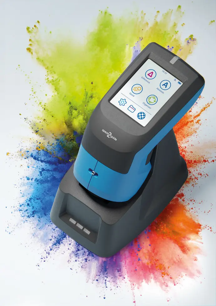 The image features a color measurement device with a touchscreen interface displayed at the top. It is primarily blue and gray, positioned against a vibrant splash of colorful media in shades of green, blue, and orange, symbolizing its purpose in color analysis.