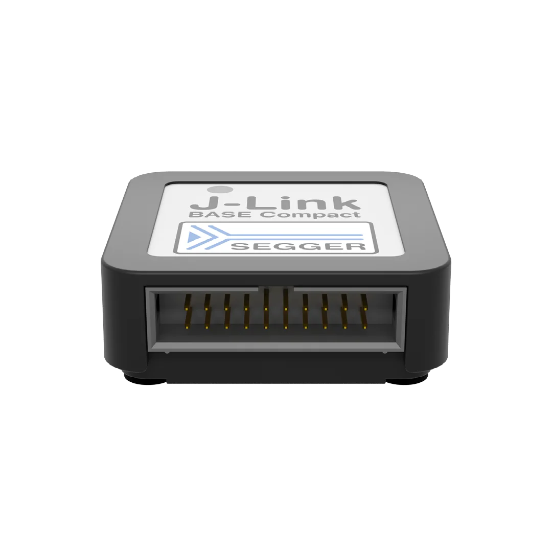 J-Link BASE Compact device by SEGGER, featuring a rectangular gray housing. The front has an opening with several metal pins inside. The top has the product name and company logo printed on a white background, indicating it is a programming and debugging tool for embedded systems.