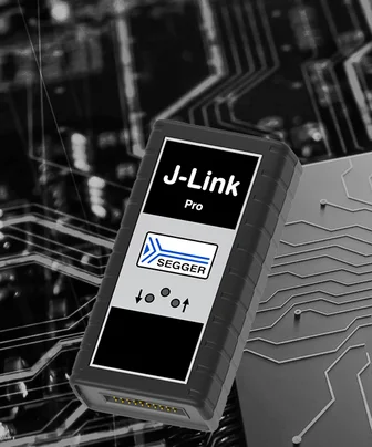A J-Link Pro debugging tool is prominently displayed against a circuit board background. The device features a black casing with the "J-Link Pro" label and the SEGGER logo, along with control icons for functionality. It is designed for programming and debugging embedded systems.