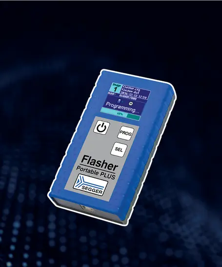 Image of a blue electronic device labeled "Flasher Portable PLUS" from SEGGER. The device features a small screen displaying a programming progress indicator and three buttons: "PROG," "SEL," and a power button. The background is a blend of dark tones with digital patterns.